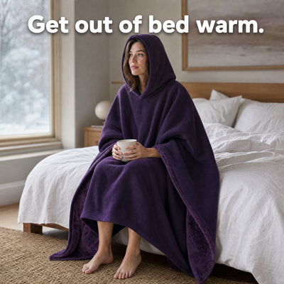 Woman sitting on her bed wrapped in a plum HeavyHug. Get out of bed warm.